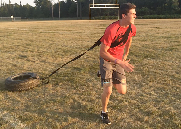 An image of a youth athlete pulling a tire as he does sprints