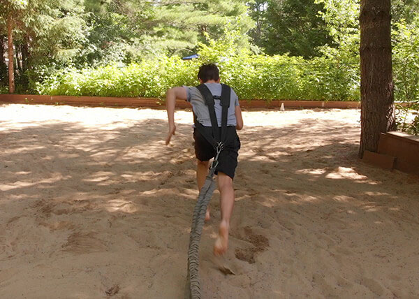 an athlete running in the sand attached to a resistance band