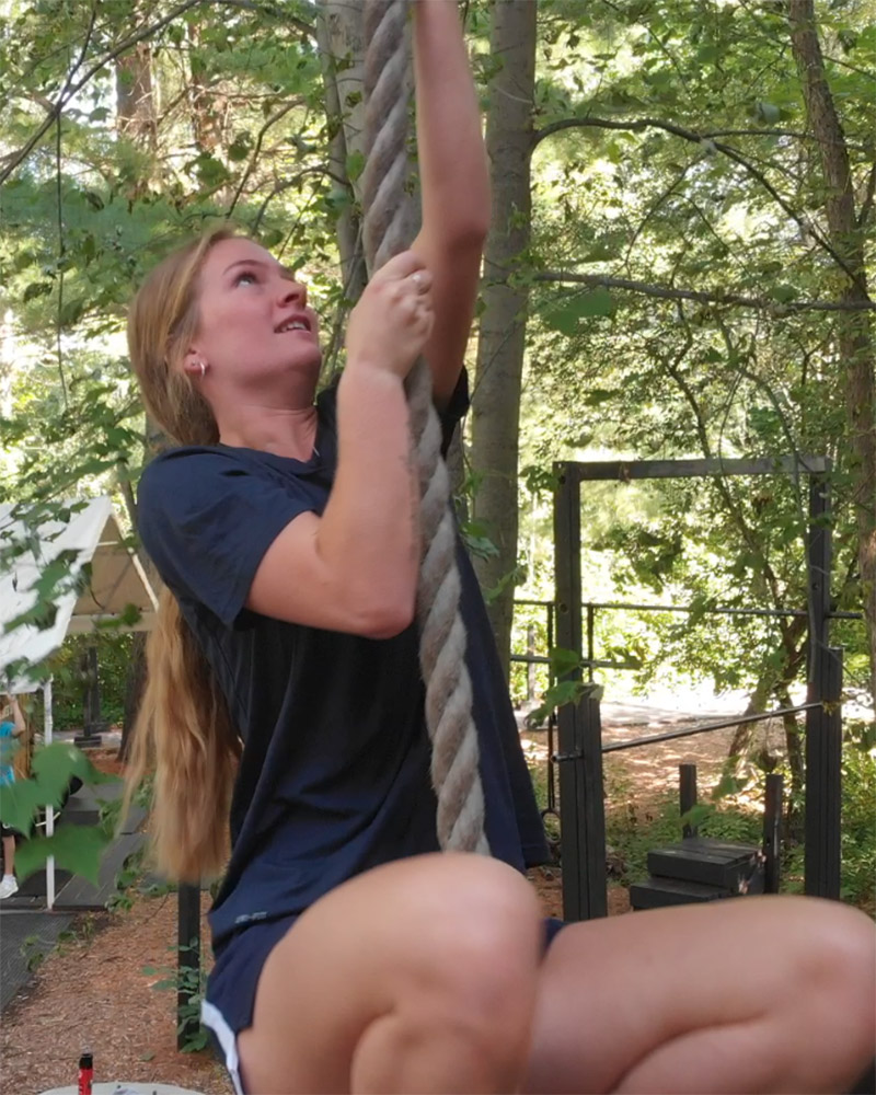 a female athlete climbing a rope outside