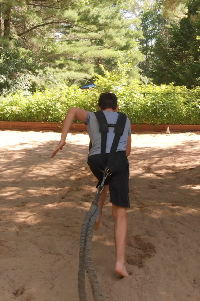 an athlete running sprints in the sand with a resistance band